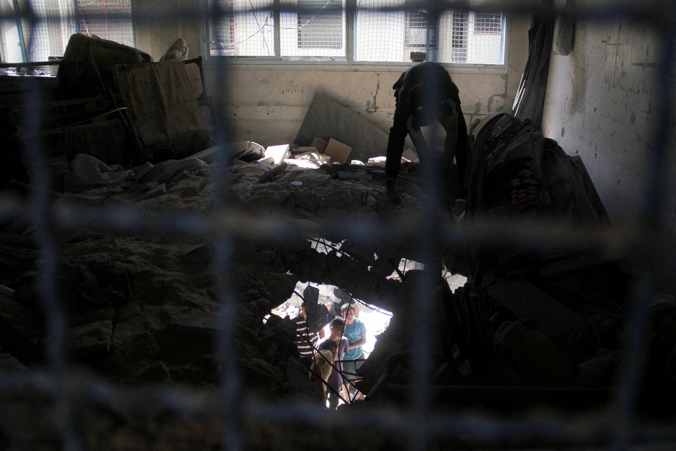Palestinos em meio a escombros de escola atingida por ataques aéreos de Israel — Foto: REUTERS/Mahmoud Issa