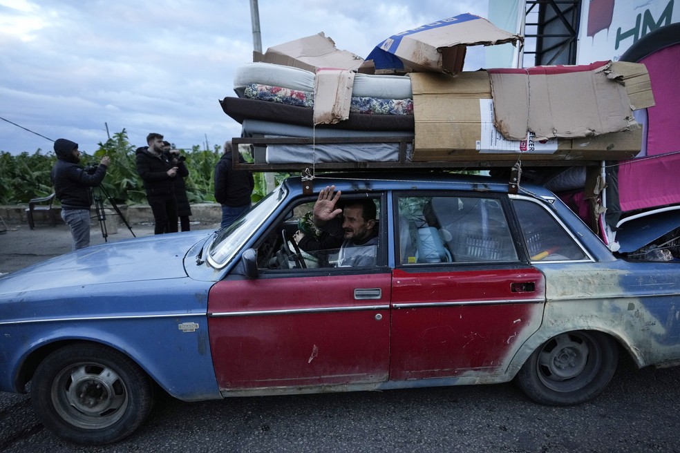 Um homem que está retornando para sua vila acena enquanto carrega seus pertences em seu carro, após o início do cessar-fogo entre o Hezbollah e Israel na madrugada de quarta-feira (27), em Tiro, no Sul do Líbano — Foto: Hussein Malla/AP