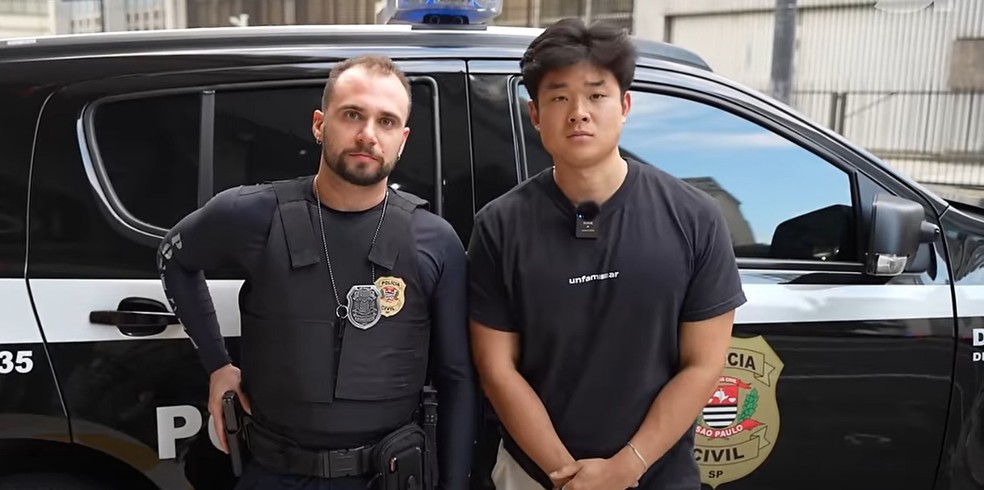 Youtuber posa ao lado de policial civil durante documentário em que passou 24 horas com a polícia — Foto: Reprodução/YouTube