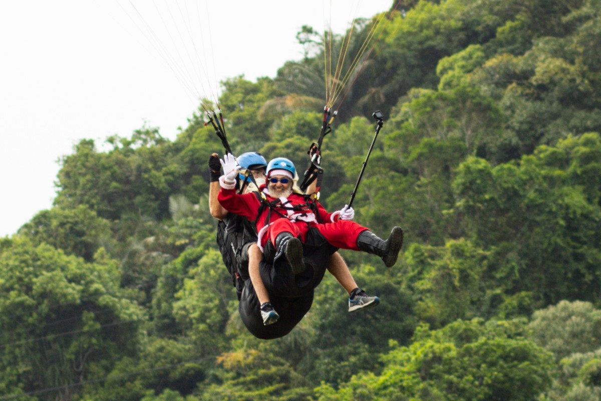 Papai e Mamãe Noel saltam de parapente em programação especial de Natal em São Vicente