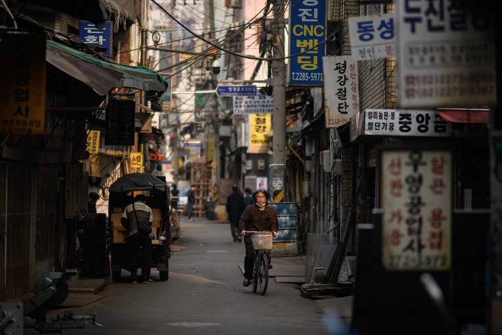 Um homem anda de bicicleta por um beco de oficinas de metal no distrito de Euljiro, em Seul, na Coreia do Sul — Foto: Ed Jones/AFP