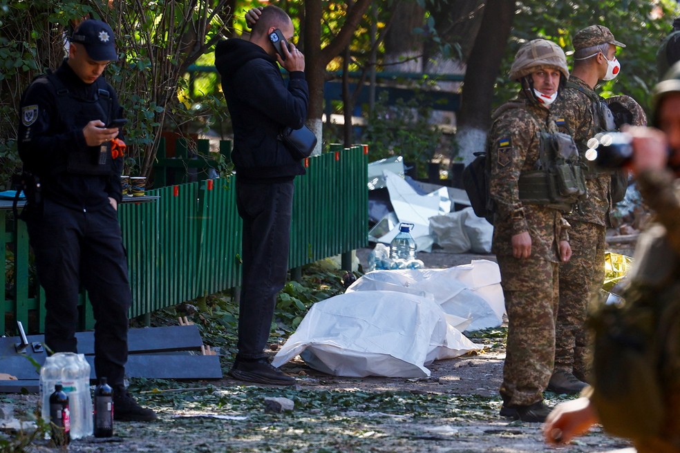 Policiais e bombeiros ao lado de corpos retirados de edifício residencial em Pryluky, em Chernigov, na Ucrânia, atingido por ataque aéreo russo em 7 de outubro de 2026. — Foto: REUTERS/Valentyn Ogirenko