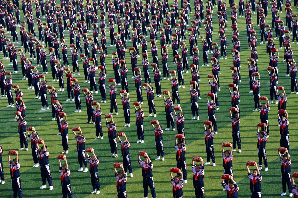 Estudantes se apresentam no campo da escola durante a cerimônia de abertura de uma reunião esportiva em Xiangyang, província de Hubei, na China  — Foto: China Daily/via Reuters