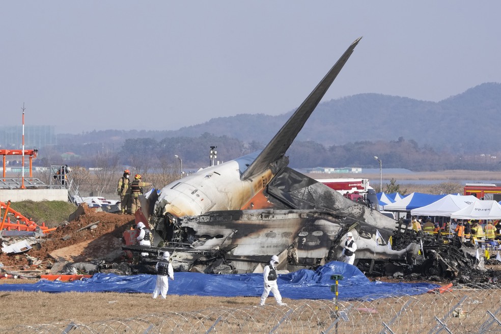 Equipes de resgate trabalham em local de acidente que deixou mais de 170 mortos na Coreia do Sul. — Foto: Associated Press