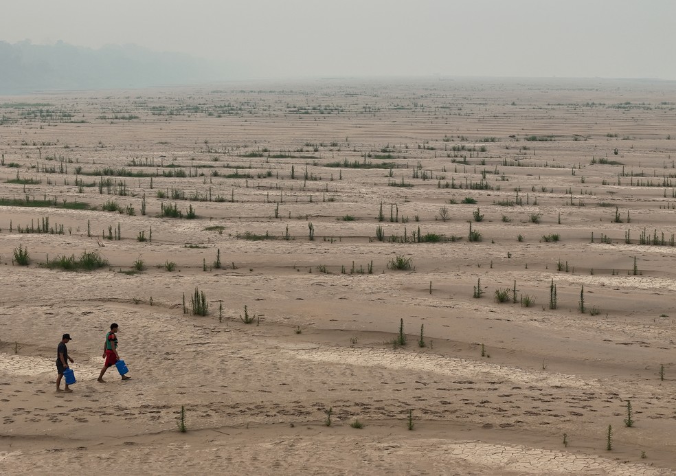 Ribeirinhos carregam gal�es de �gua enquanto atravessam bancos de areia do rio Madeira at� a comunidade Paraizinho, em meio � pior seca da hist�ria. Humait�, Amazonas. � Foto: Bruno Kelly/Reuters