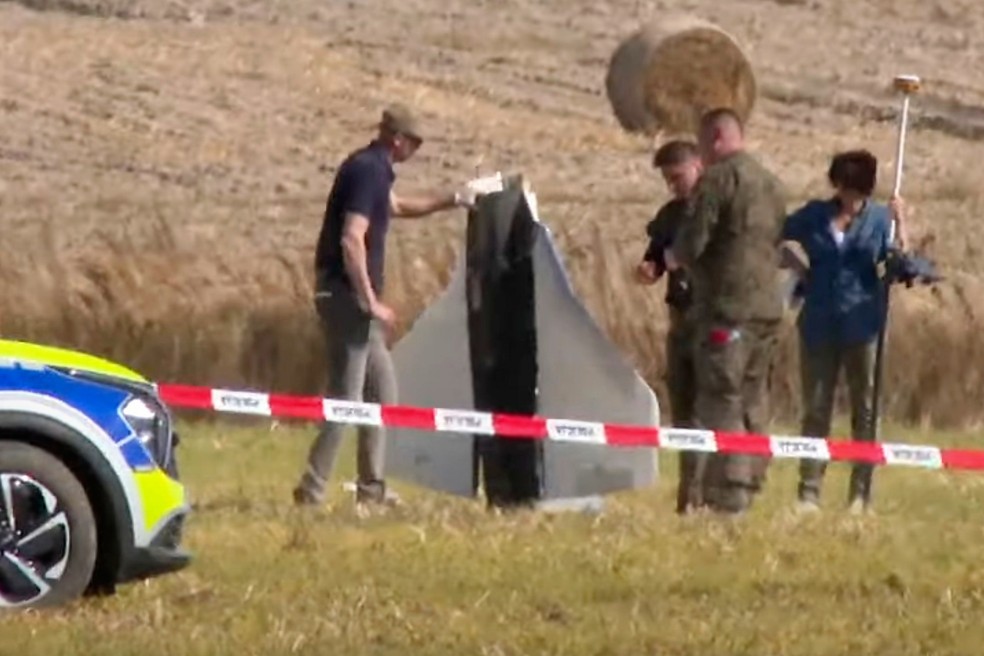 Nesta imagem feita a partir de um vídeo, policiais e policiais militares protegem partes de um objeto danificado abatido pelas autoridades polonesas em um local em Wohyń, Polônia, na quarta-feira, 10 de setembro de 2025 — Foto: Rafal Niedzielski/AP