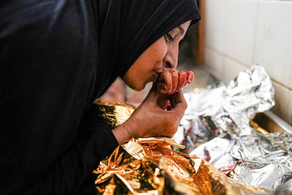 25 de junho - Uma mãe se despede do corpo de seu filho, morto após o bombardeio israelense noturno em al-Maghazi, no centro da Faixa de Gaza, no necrotério do hospital Aqsa Martyrs em Deir el-Balah, em meio ao conflito em andamento no território palestino entre Israel e o Hamas. O rosto da criança foi borrado digitalmente — Foto: Bashar Taleb/AFP