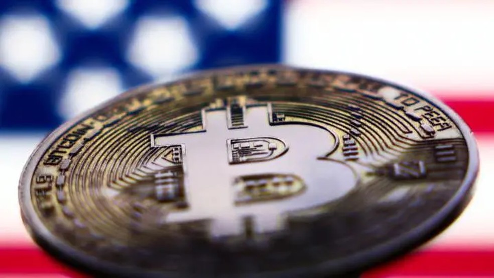 Bandeira dos EUA exibida na tela de um laptop e representação da criptomoeda Bitcoin em 6 de novembro de 2024. — Foto: Getty Image via BBC