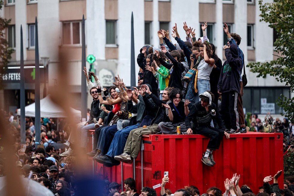 Manifestantes sentados sobre um contêiner na Place des Fêtes, em Paris, durante protesto do movimento ‘Bloquons tout’ (‘Vamos bloquear tudo’), em 10 de setembro de 2025. — Foto: Anne-Christine POUJOULAT / AFP