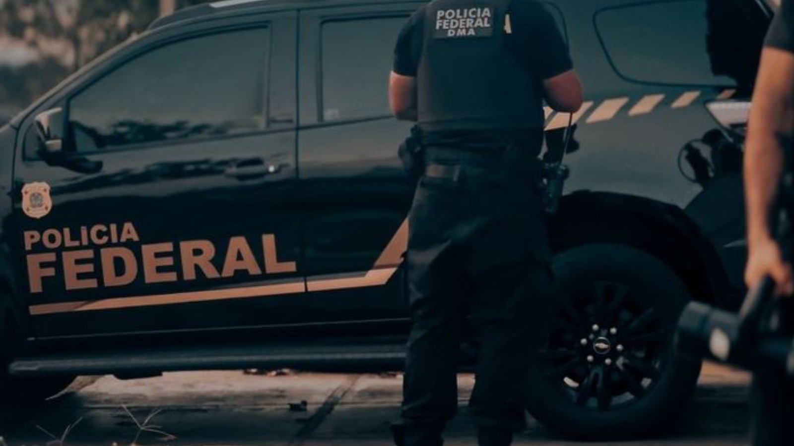 Viatura oficial da Polícia Federal do Brasil estacionada em frente a prédio moderno em Brasília.