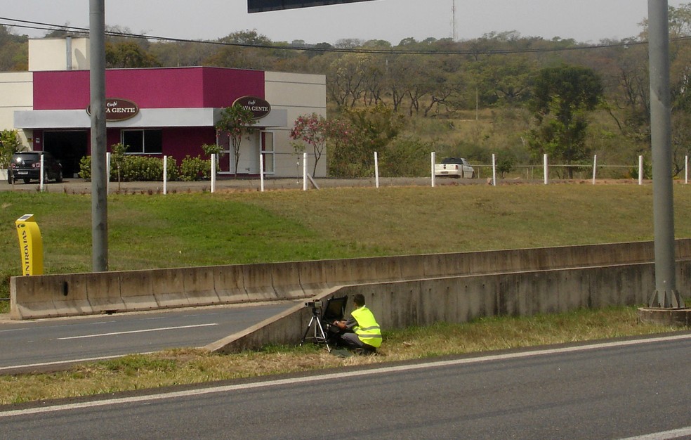 Agente de trânsito posiciona o radar atrás da mureta de proteção da rodovia — Foto: Carlos Pradini