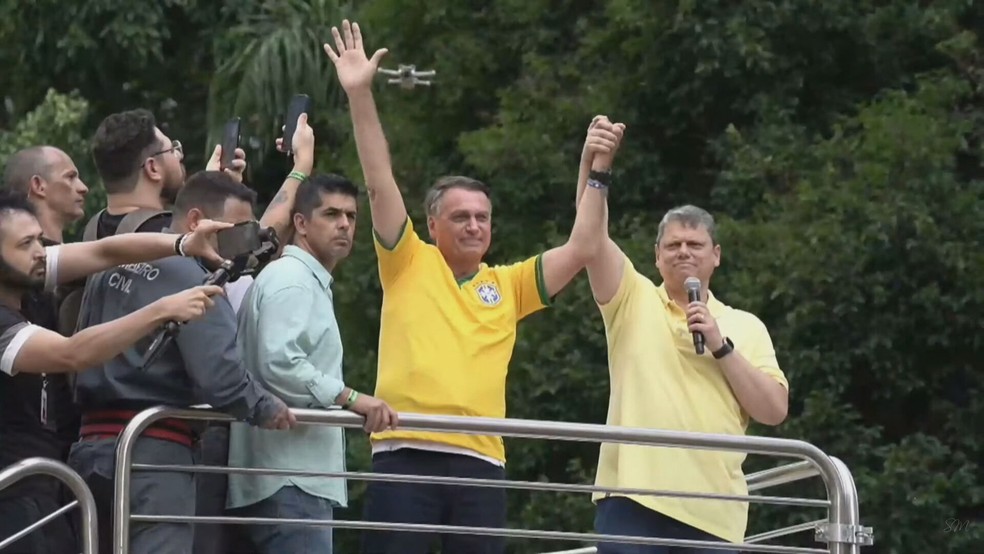 Tarcísio de Freitas estende a mão de Bolsonaro durante ato na Paulista neste domingo (25). — Foto: Reprodução/Youtube