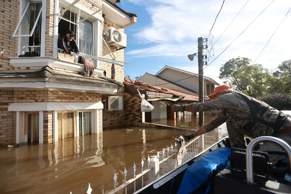 Homem ilhado recebe ajuda em Canoas — Foto: Diego Vara/Reuters