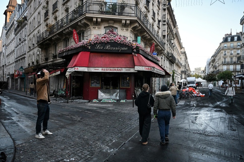 Pedestres em Paris passam em frente a restaurante depredado nos protestos na região central de Paris. — Foto: MATTHIEU RONDEL/AFP