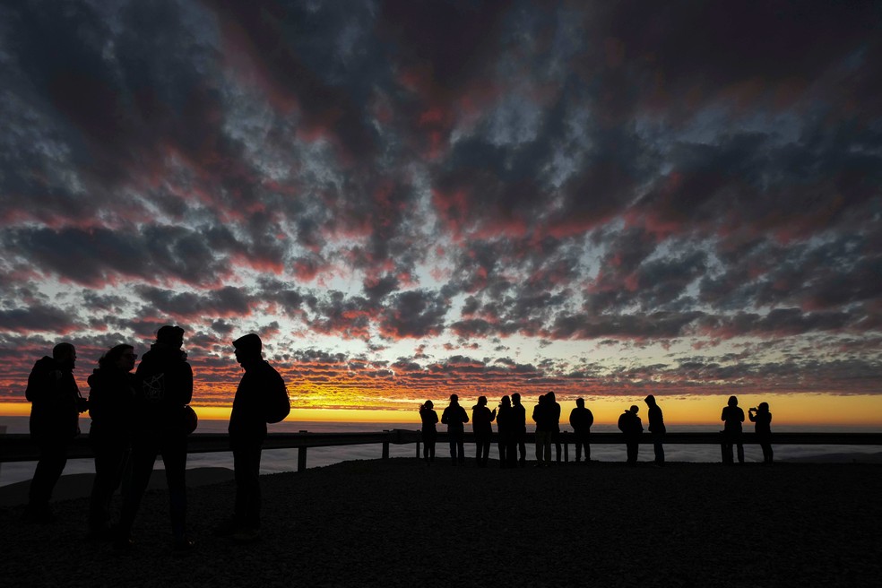 Astrônomos são silhuetados contra o céu ao pôr do sol no Observatório Paranal, no Deserto do Atacama, Chile — Foto: AP/Esteban Felix