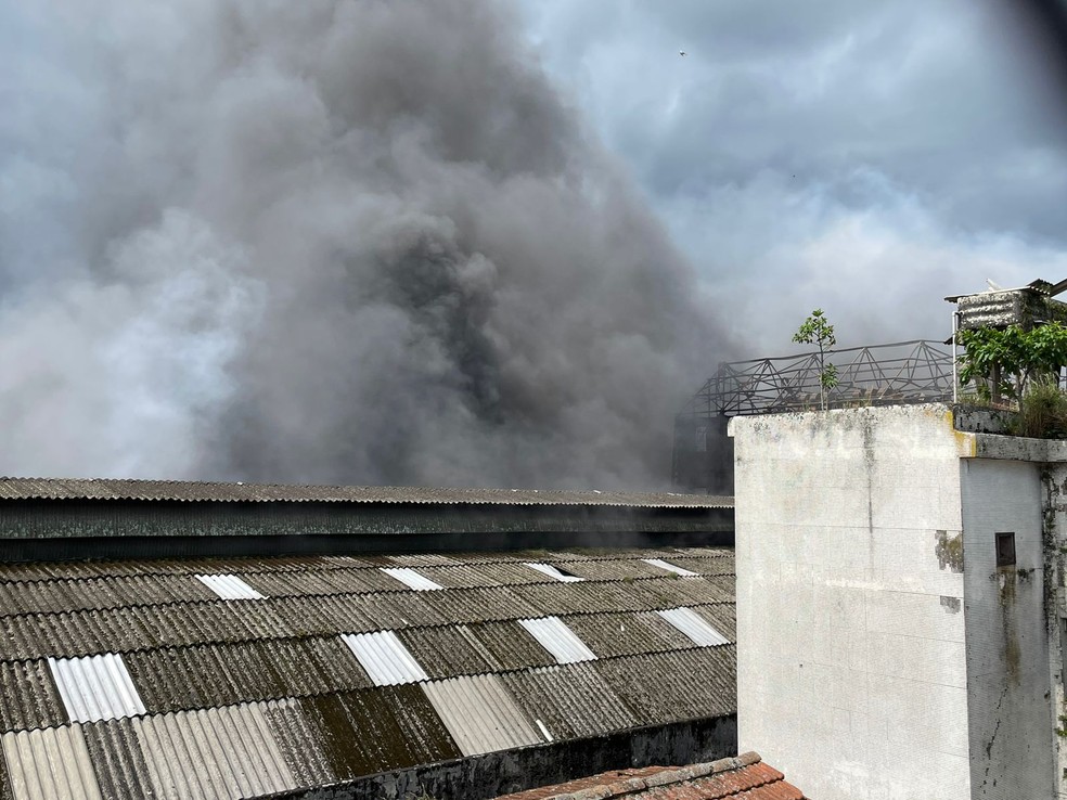 Por volta das 14h, equipes dos bombeiros seguem combatendo chamas em galpões, no Centro de Santos (SP) — Foto: Thais Rozo/g1