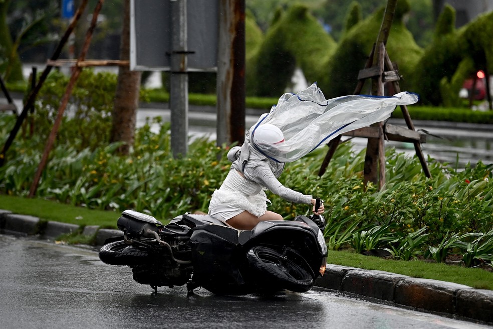 Mulher é derrubada de moto pelo vento do tufão Yagi na cidade de Hai Phong, na China, neste sábado (7) — Foto: Nhac Nguyen/AFP