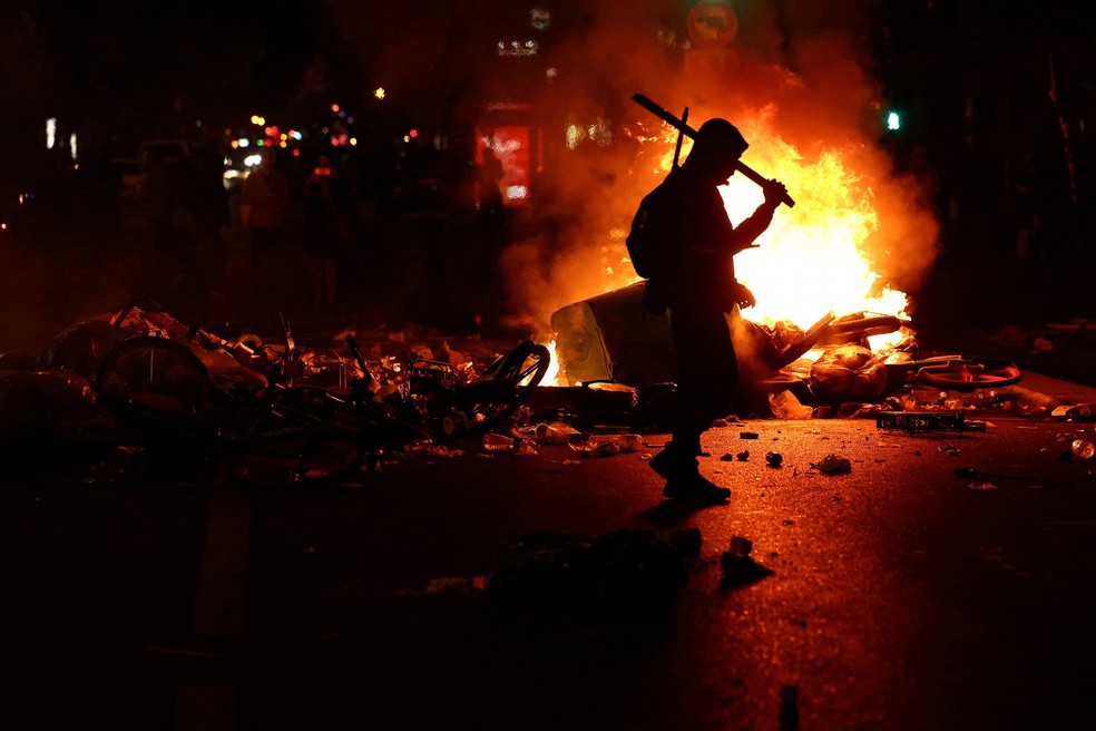 Homem caminha diante de fogo em meio a manifestação em Paris, em 18 de outubro de 2026. — Foto: Abdul Saboor/ Reuters