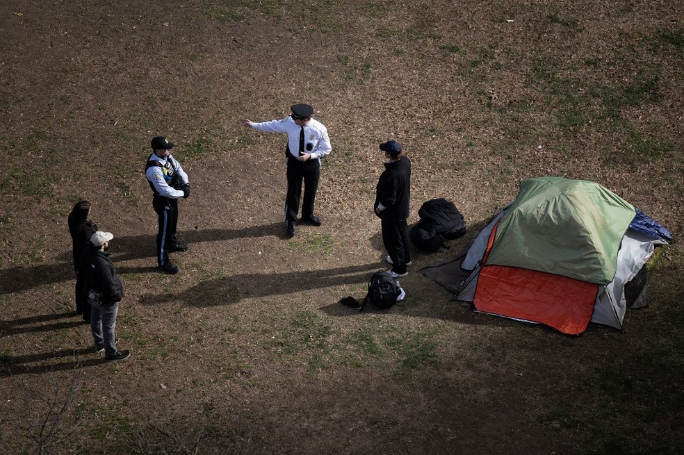 Policiais falam com um homem sem-teto que se recusa a sair da McPherson Square, em Washington, em fevereiro de 2023, após policiais retirarem um acampamento de pessoas em condição de rua — Foto: Brendan Smialowski/AFP