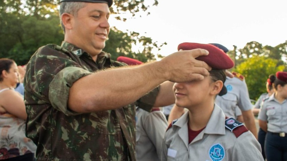 Jovem fazendo saudação militar com a mão na testa, honra