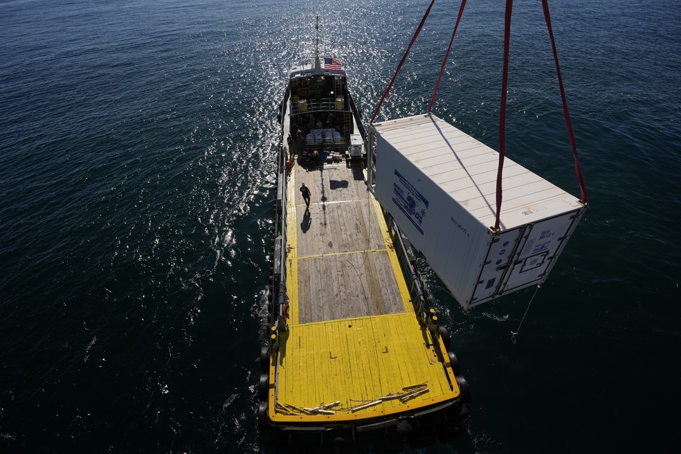 Um contêiner de suprimentos é içado do Gaspee, embarcação de transporte de tripulação, para a plataforma Liftboat Robert durante operação da Expedição 501 no Atlântico Norte, em 19 de julho de 2025. — Foto: Carolyn Kaster/AP