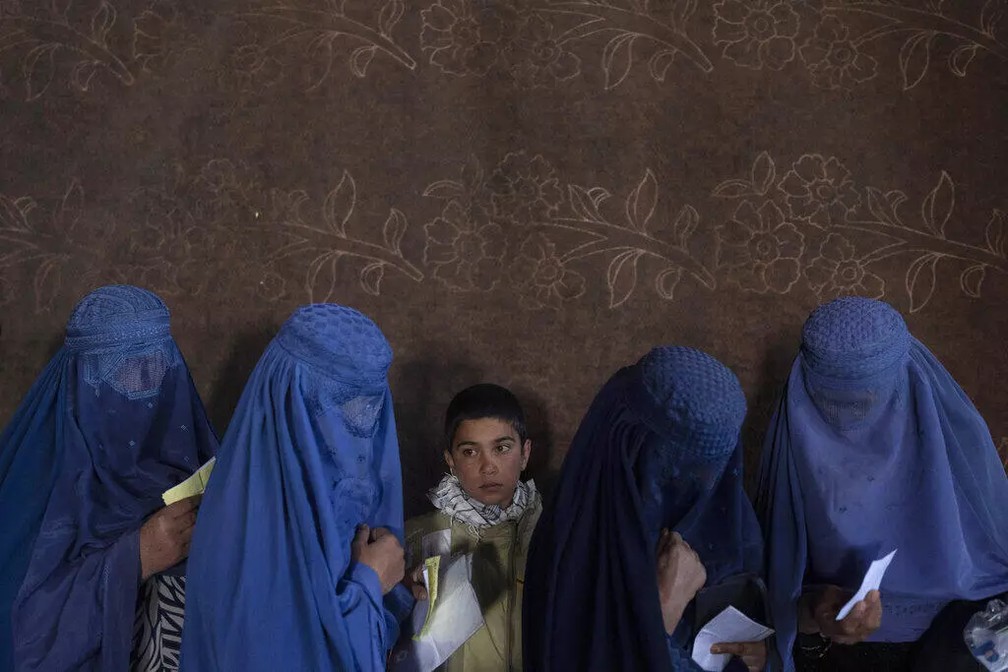 Mulheres afegãs esperam para receber doações num ponto de distribuição do Programa Mundial de Alimentos, em Cabul, Afeganistão, 20 de novembro de 2021 — Foto: AP - Petros Giannakouris