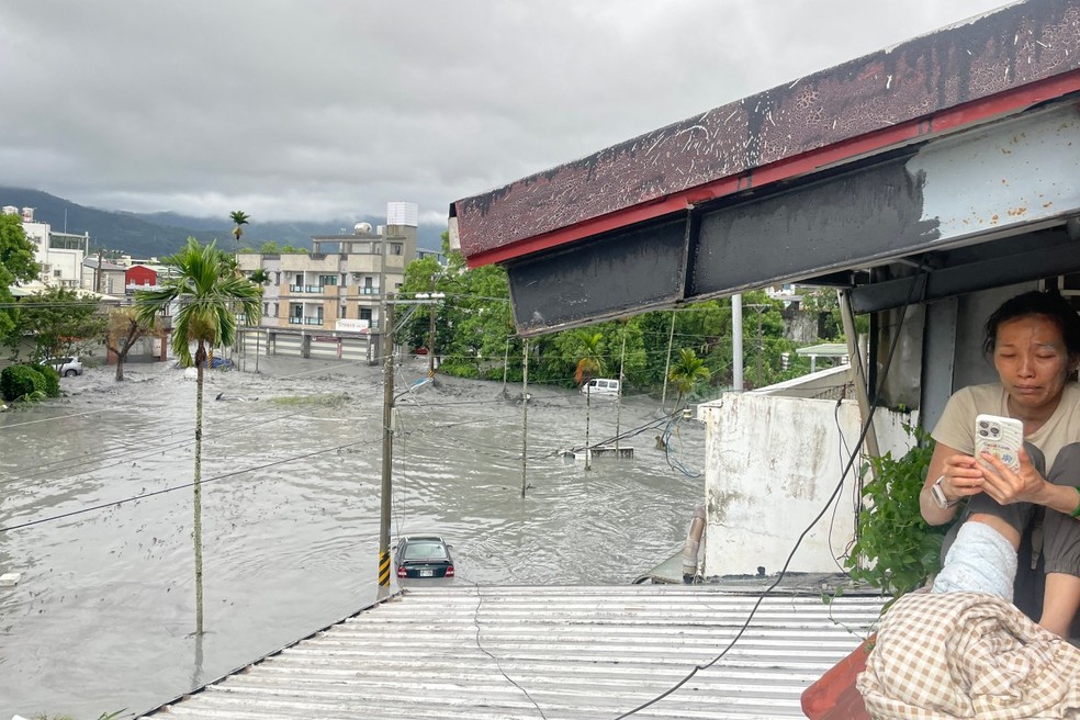 Mulher se abriga no telhado de uma casa durante enchente em Taiwan, em 23 de setembro de 2025 — Foto: AFP