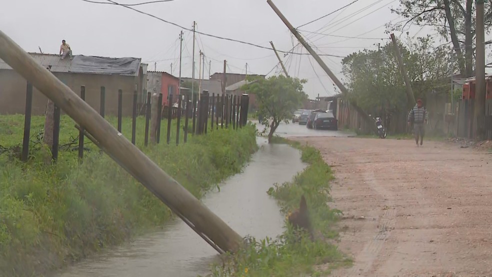Postes cados e homem em cima de telhado em Camaqu — Foto: Reproduo/RBS TV