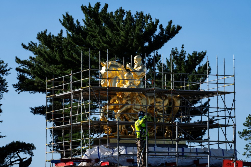 Um trabalhador da construção remove andaimes perto das estátuas recém-douradas na instalação As Artes da Guerra na Ponte Memorial, em Washington, D.C., EUA. — Foto: REUTERS/Nathan Howard
