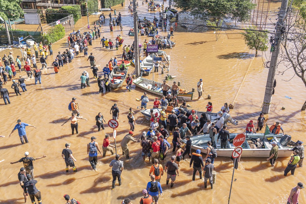 Equipes de bombeiros, policiais, militares e civis voluntários ajudam a resgatar e abrigar moradores que tiveram casas inundadas em Porto Alegre. — Foto: JORGE LANSARIN/ENQUADRAR/ESTADÃO CONTEÚDO