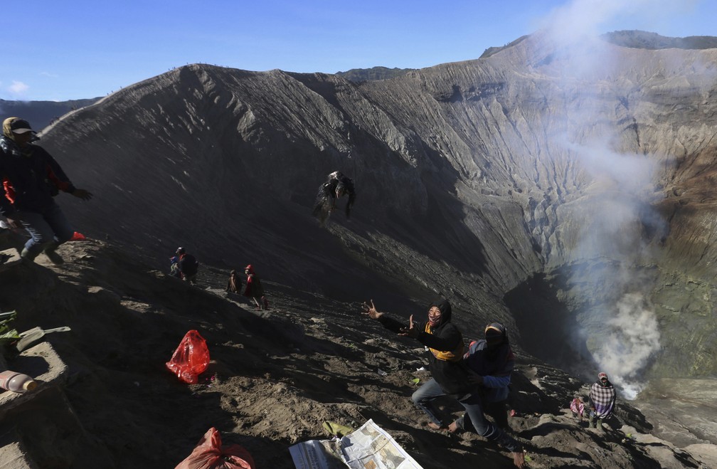 Homem tenta pegar galinha durante cerimônia de Yadnya Kasada no monte Bromo, na Indónesia — Foto: ASSOCIATED PRESS