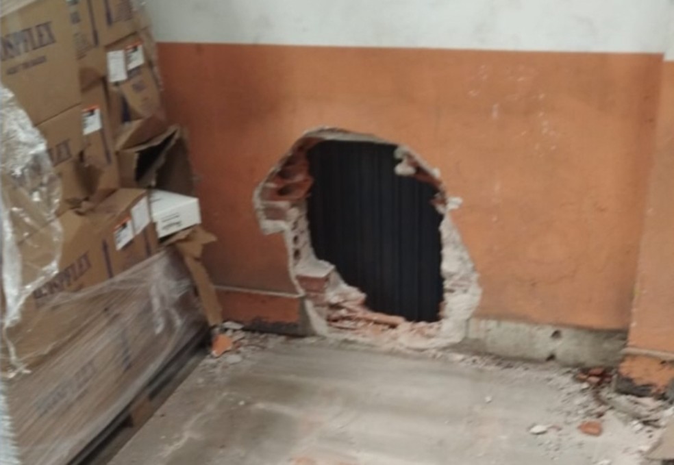 Buraco feito na parede para invasão na empresa. — Foto: TNOnline/Agex Transportes Urgentes