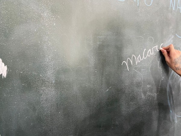 O adolescente Matheus (nome fictício) escreve na lousa a palavra "macarrão", ao ser perguntado sobre uma comida que deseja comer — Foto: Larissa Pandori/g1