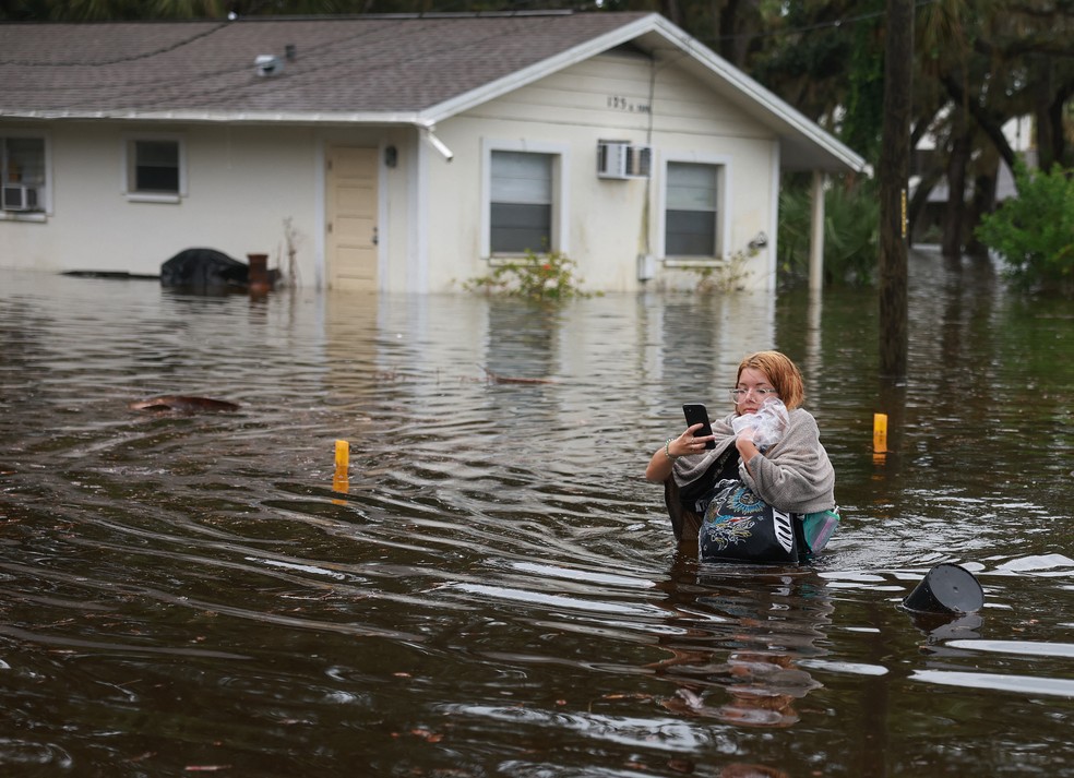 Mulher atravessa enchente depois de ter que evacuar sua casa em Tarpon Springs, Flórida, em 30 de agosto de 2023 — Foto: Joe Raedle/Getty Images North America/Getty Images via AFP