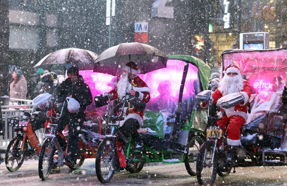 Guias turísticos fantasiados de papai noel circulam na área de Times Square, em Nova York, em meio a uma nevasca que atingiu a cidade em 26 de dezembro de 2025 — Foto: AFP
