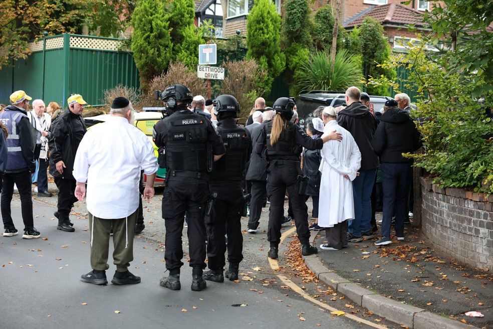 Policiais orientam pessoas presentes, algumas delas com a veste judaica quipá, perto de local de ataque em sinagoga em Manchester, no Reino Unido, em 2 de outubro de 2025. — Foto: REUTERS/Phil Noble
