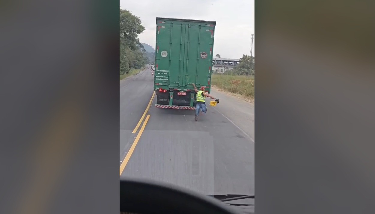Homem se pendura em caminhão, escorrega e quase é atropelado em rodovia de SC; VÍDEO
