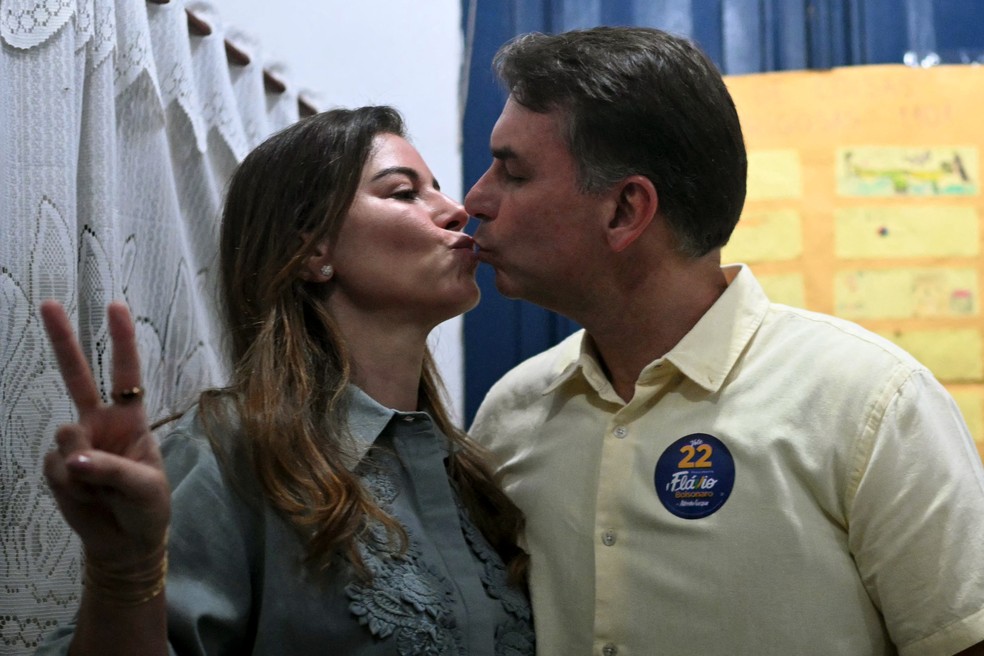 O candidato do PL à Presidência, Flávio Bolsonaro, beija a esposa, Fernanda Bolsonaro, depois de votar na Escola Municipal Barão Homem de Mello, em Vila Isabel, na Zona Norte do Rio, no dia 25 de outubro de 2026 — Foto: Mauro Pimentel/AFP