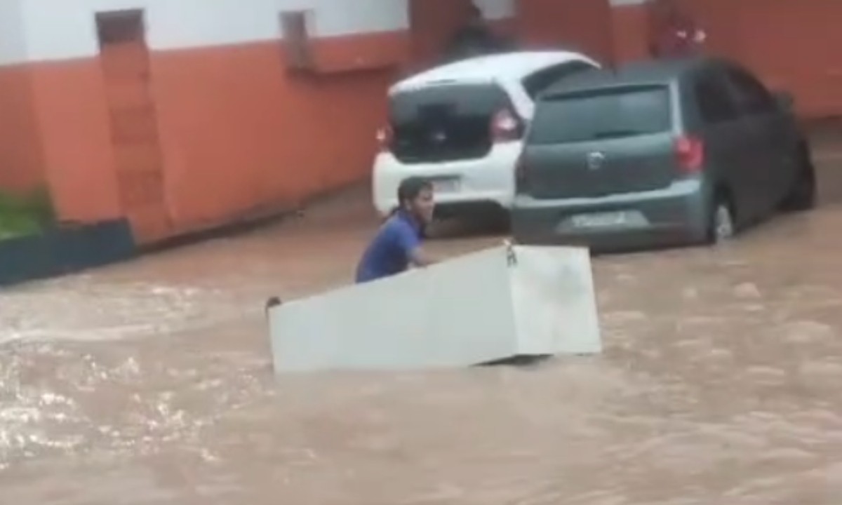 Homem usa geladeira para 'navegar' em avenida alagada após forte chuva em Manaus