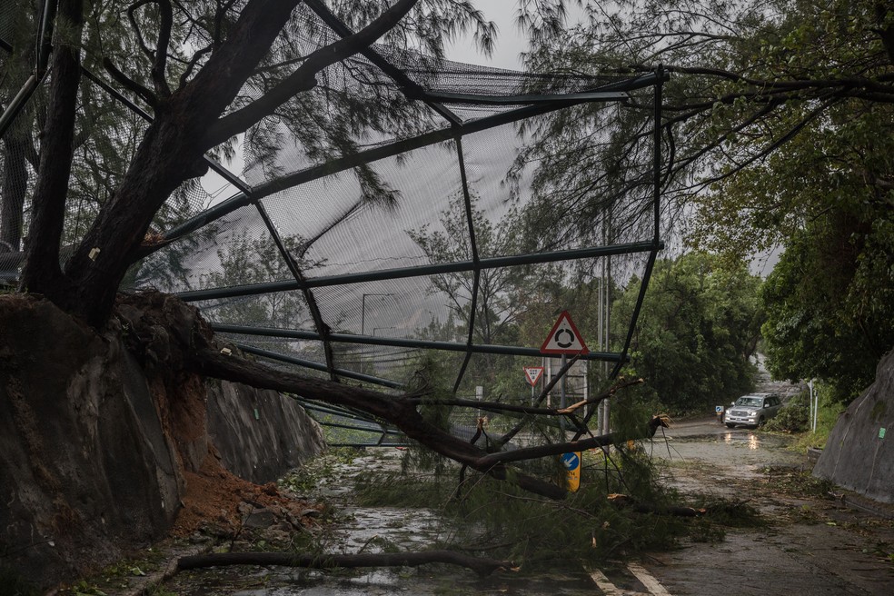 Um motorista passa por uma cerca caída de um campo de golfe após o tufão Saola, perto de uma vila costeira em Hong Kong, em 2 de setembro de 2023 — Foto: DALE DE LA REY / AFP