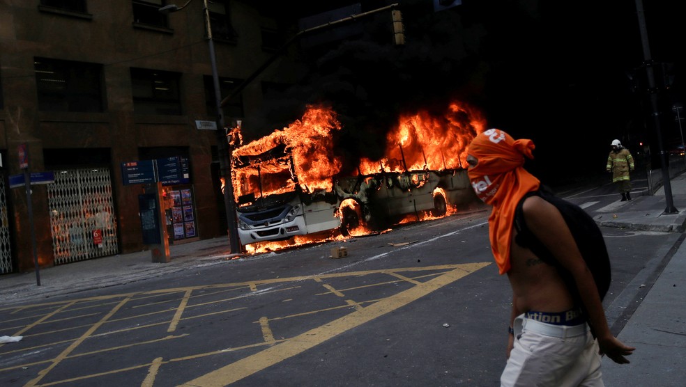 Um manifestante caminha perto de um ônibus em chamas durante protesto contra medidas de austeridade do Governo estadual do RJ perto da Assembleia Legislativa do Rio de Janeiro (Alerj) — Foto: Ricardo Moraes/Reuters
