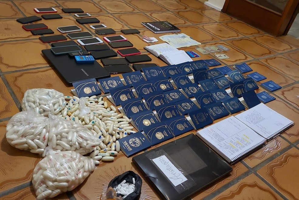 Drogas e passaportes apreendidos em casa onde 33 pessoas eram treinadas para engolir capsulas de cocaína — Foto: Divulgação