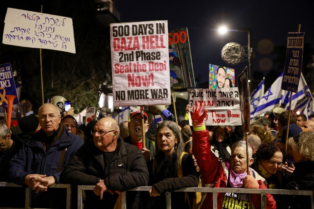 Cartazes pedindo que o acordo de cessar-fogo seja mantido e a guerra termine em protesto na porta da casa de Benjamin Netanyahu — Foto: Menahem Kahana / AFP
