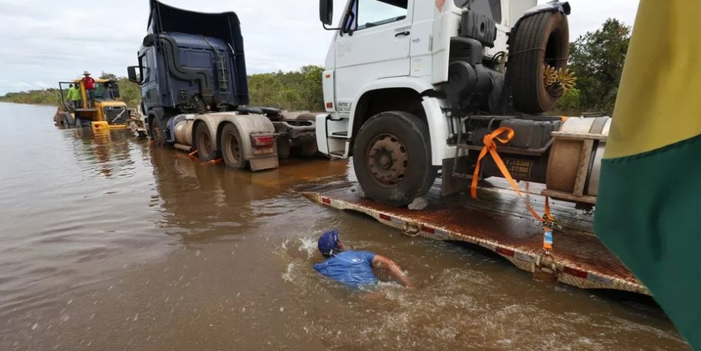 Homem nada ao lado de carretas na BR-364, inundada pelo Rio Madeira, em 2014 — Foto: Sérgio Vale/Secom Acre/Arquivo