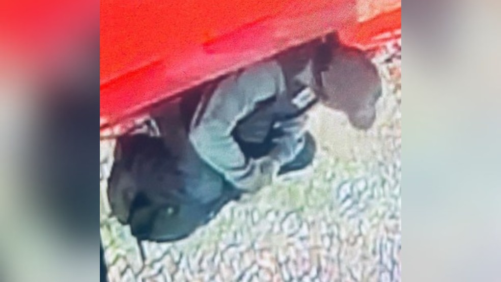 Suspeito de furto sentado em frente à loja invadida em Uberaba — Foto: Polícia Militar/Divulgação