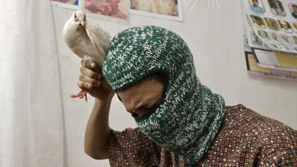 Acompanhamos Ade em uma visita a um curandeiro tradicional, em uma cerimônia que envolvia o sacrifício de uma pomba para vinculá-lo à riqueza — Foto: BBC