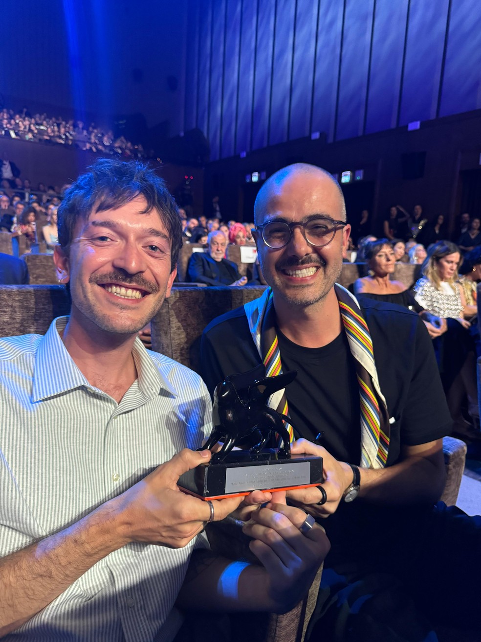 Os roteiristas Heitor Lorega (à dir.) e Murilo Hauser (à esq.) com o troféu de Melhor Roteiro do Festival de Veneza, entregue por 'Ainda Estou Aqui' — Foto: Arquivo Pessoal