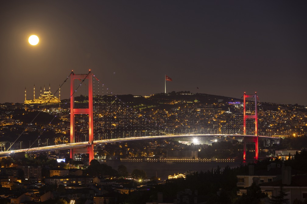 A superlua surge atrás da mesquita Camlica e da Ponte dos Mártires em Istambul, na Turquia. — Foto: AP