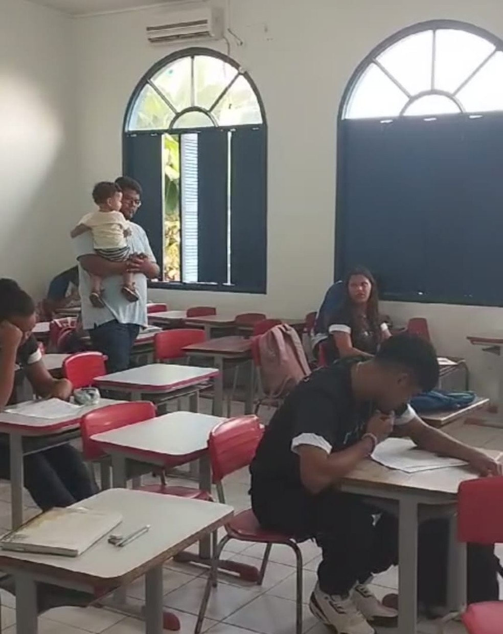 Professor Yan Dias segurou filho da aluna para que ela pudesse se concentrar na prova de português — Foto: Reprodução