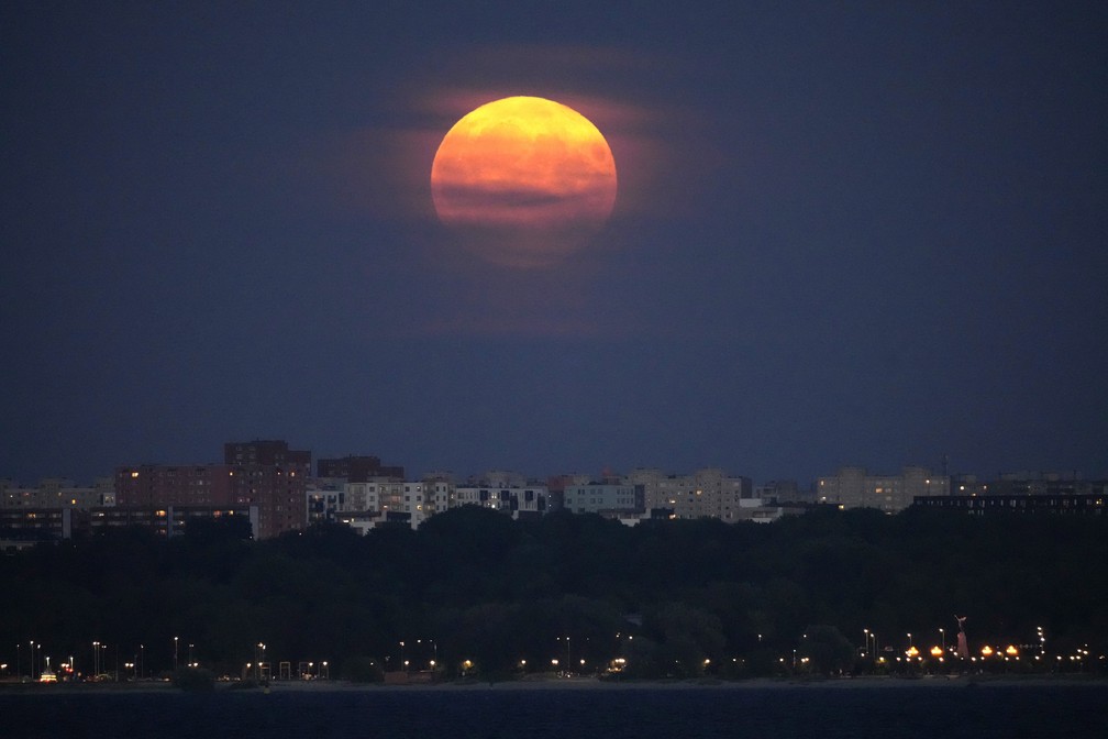 A superlua surge através das nuvens sobre o centro da cidade de Tallinn, na Estônia. — Foto: AP